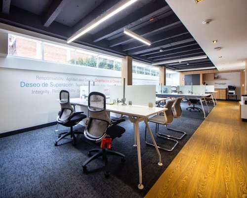A modern shared workspace setup in Mexico City showing clean tables and balanced overhead lighting panels