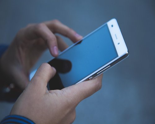 A person using a smartphone in a dimly lit public transit setting, observing screen distance