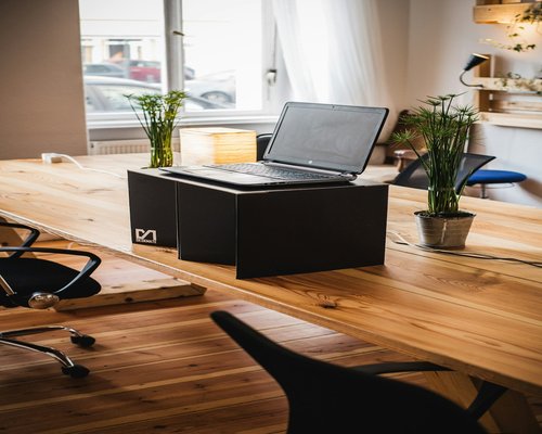 Digital device with adjusted display setup on a wooden desk in a coworking space