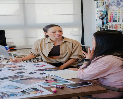 Two lifestyle writers discussing daily ergonomics and workplace wellbeing in a creative studio